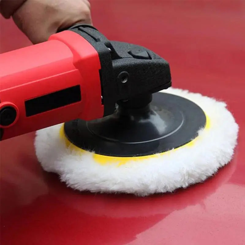 Red electric car polisher with a white polishing pad on a red car surface.