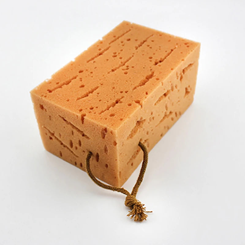 Close-up of a rectangular orange sponge with a tan rope for hanging.
