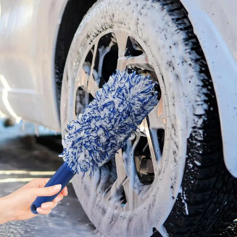 Cleaning car wheel with blue microfiber wheel brush and soap.