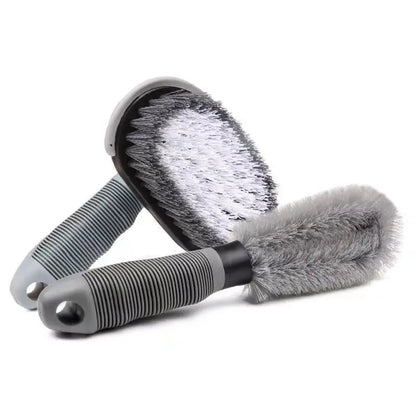 Two detailing brushes, one oval with white bristles and one round with gray, both with gray striped handles.