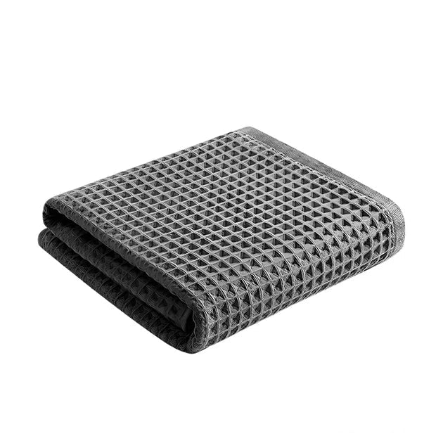 Folded gray waffle weave towel. Highly absorbent and quick-drying.
