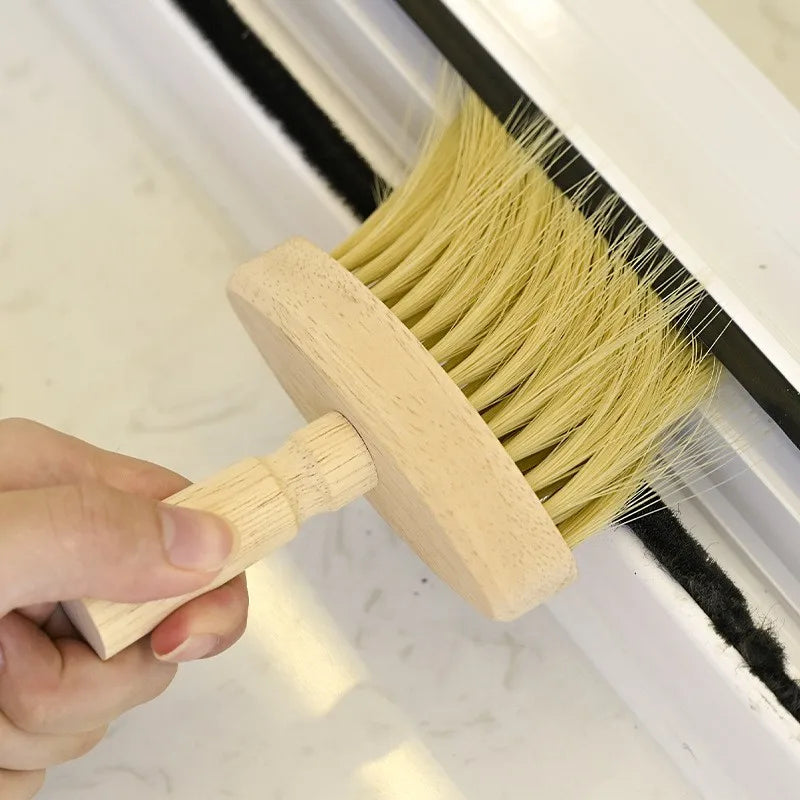 Window track cleaning brush with wooden handle removing debris.
