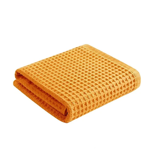 Folded orange waffle weave towel. Absorbent and soft texture.