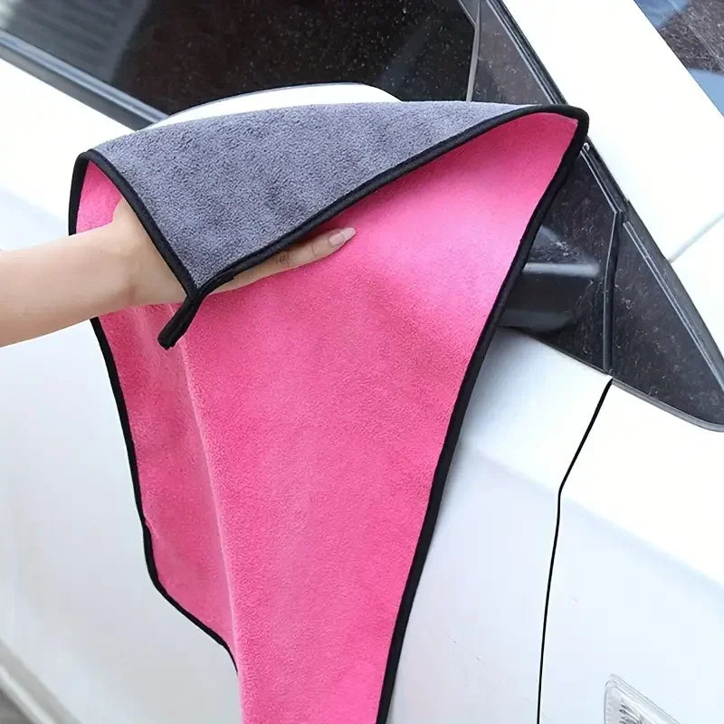 Pink and gray microfiber towel cleaning a white car mirror.